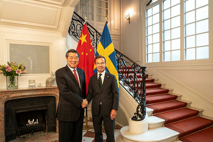 Statsminister Ulf Kristersson tillsammans med Kinas vicepremiärminister He Lifeng i Sagerska huset framför kinesisk och svensk flagga.