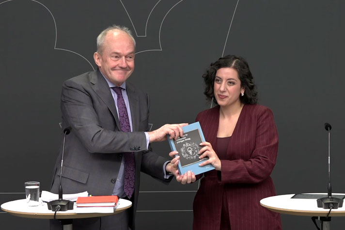 Två personer håller i en bok som de gemensamt visar upp.