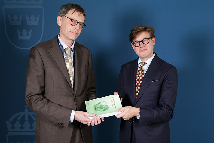 David Sikström och utredaren håller i ett exemplar av utredningens betänkande