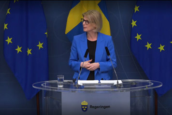 Finansminister Elisabeth Svantesson i en talar framför en fond av EU- och Sverigeflaggor