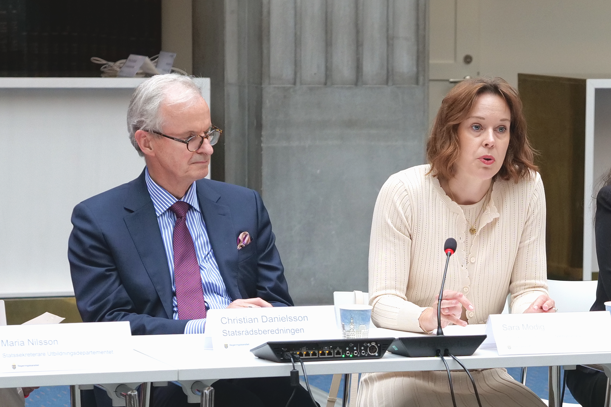 Statssekreterare Sara Modig håller ett tal. Bredvid henne sitter statssekreterare Christian Danielsson.