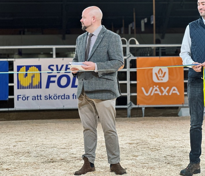 Landsbygdsminister Peter Kullgren står bakom ett gulblått band.