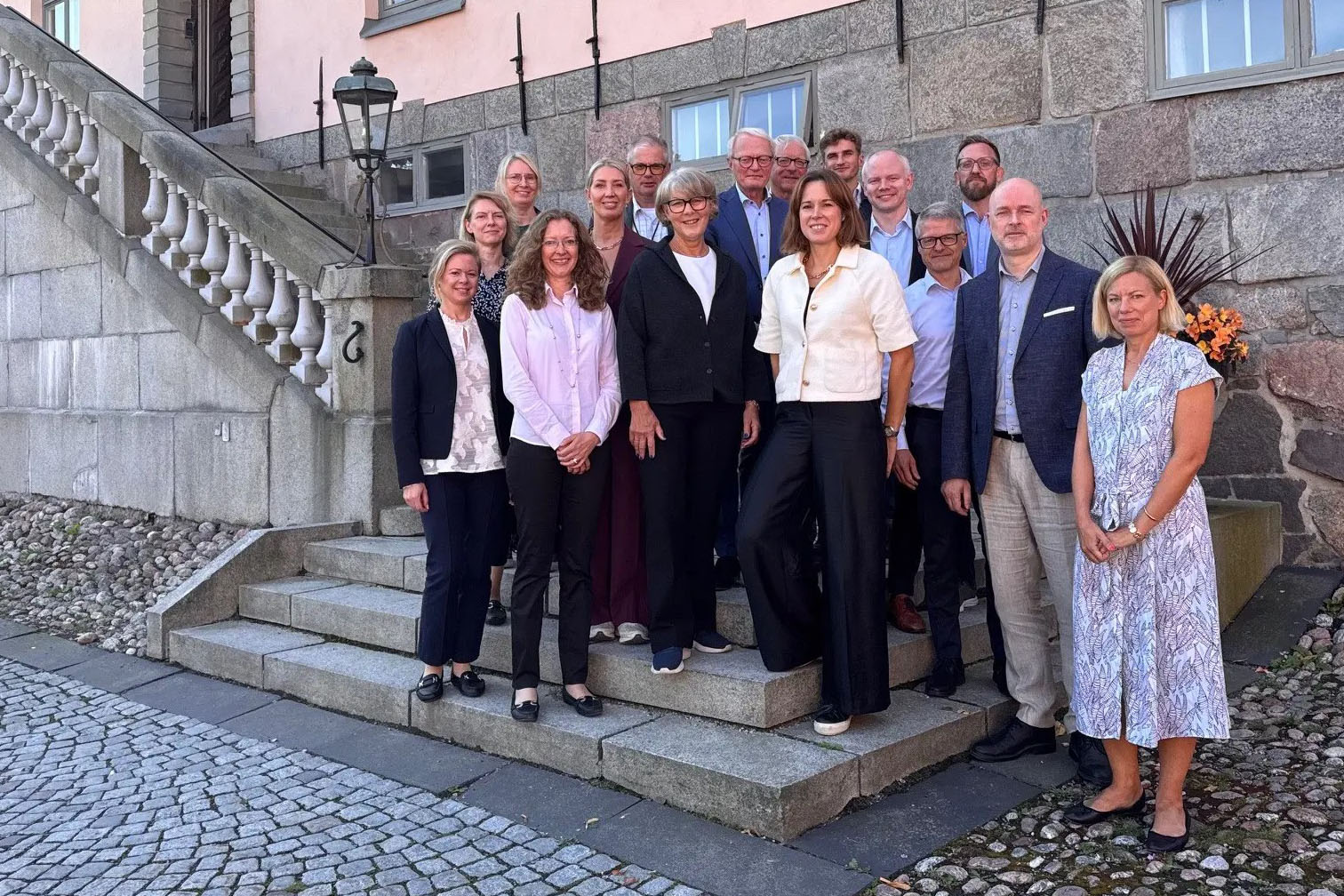 Gruppbild på förenklingsrådet och kanslimedarbetarna. De står på en trappa utanför en gammal byggnad.