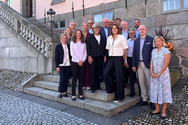 Gruppbild på förenklingsrådet och kanslimedarbetarna. De står på en trappa utanför en gammal byggnad.