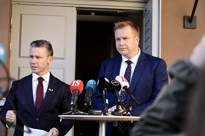 till vänster i bild står Pål Jonson bredvid Antti Kaikkonen. Framför dem finns en bord med mikrofoner.
