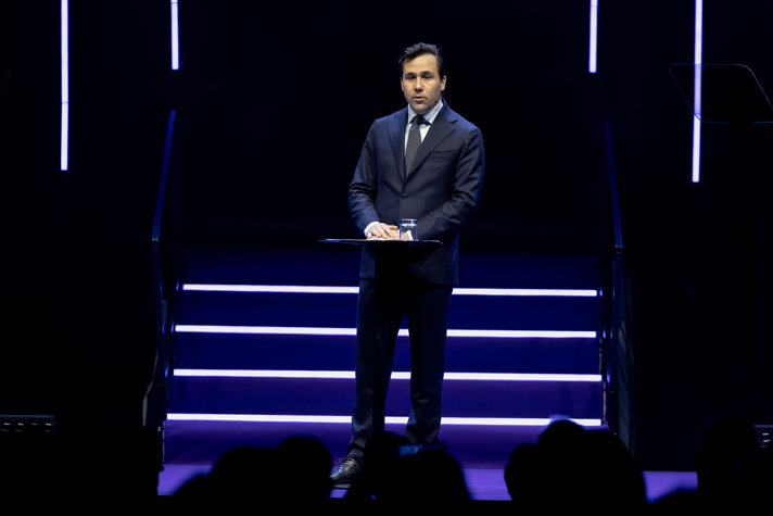 Bistånds- och utrikeshandelsminister Benjamin Dousa står på e scen och talar..