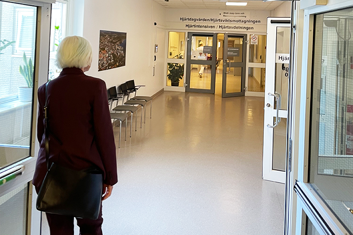 Kvinna går i sjukhuskorridor. I bakgrunden skyltar med texten "Hjärtdagvården"