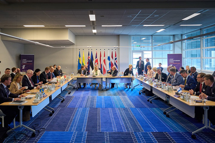 Foto på personer som sitter vid ett U-format konferensbord.