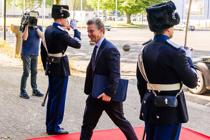 Foto på Försvarsminister Pål Jonson som går förbi två uniformerade vakter på en röd matta.