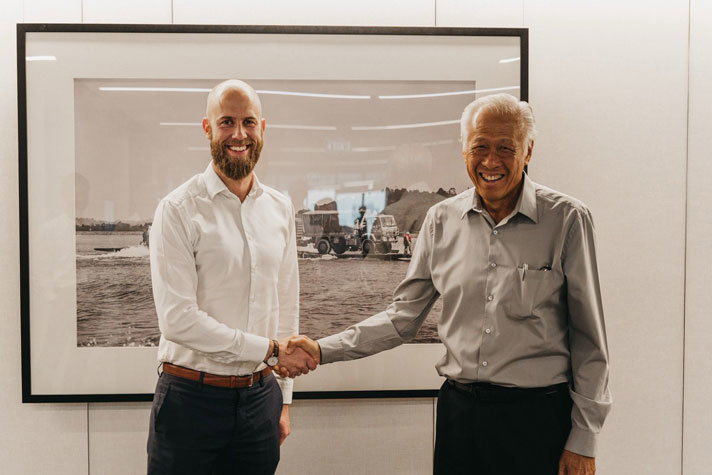 Carl-Oskar och Ng Eng Hen skakar hand och ler in i kameran.
