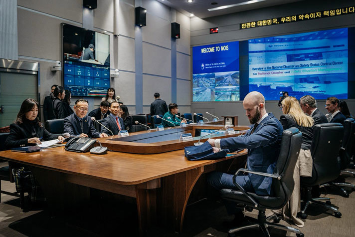 Carl-Oskar sitter vid ett mötesbord omgiven av skärmar och andra mötesdeltagare.
