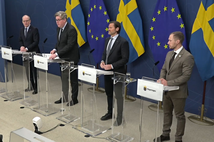 Justitieminister Gunnar Strömmer flankerad av Pontus Andersson Garpvall (SD), ledamot i justitieutskottet, Martin Melin (L), rättspolitisk talesperson och Ingemar Kihlström (KD), kriminalvårdspolitisk talesperson, bakom var sin talarstol.