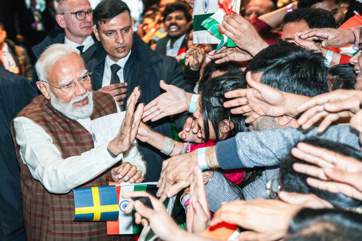 Indiens premiärminister Modi träffar en stor grupp personer som står med svenska och indiska flaggor i händerna.