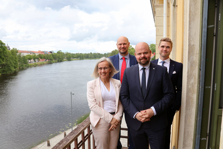 De står på en terrass med en sjö i bakgrunden.