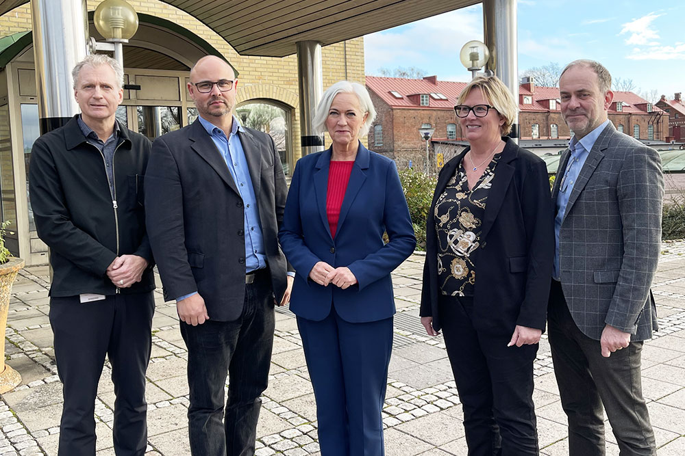 Foto på fem personer framför en entré.