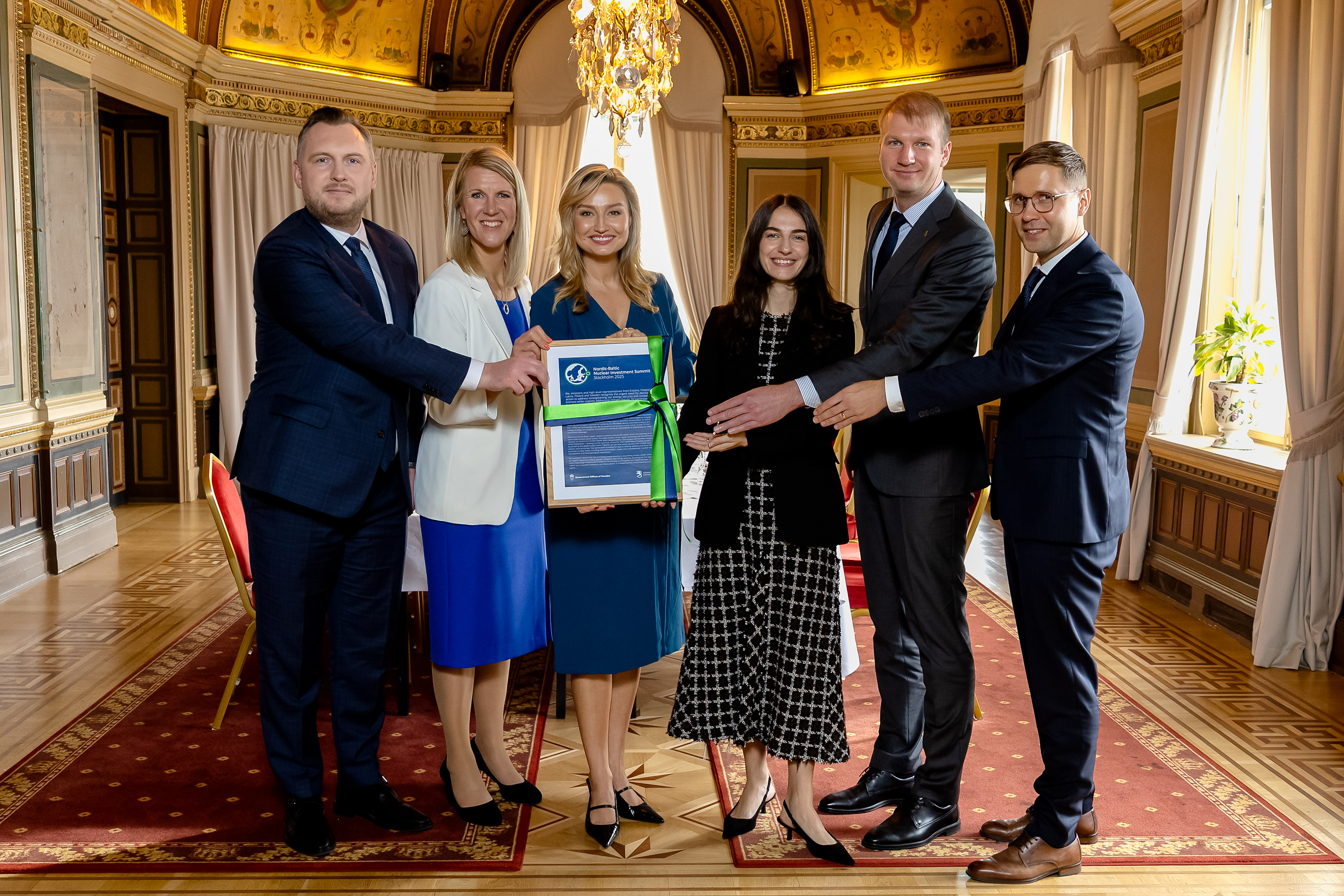 Sex personer står bredvid varandra inomhus och håller upp den inramade deklarationen..