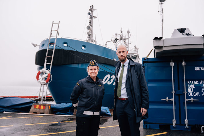 Kustbevakningens generaldirektör Therese Mattsson och minister för civilt försvar carl-Oskar Bohlin står framför ett av Kustbevakningens skepp på en gråmulen dag. 