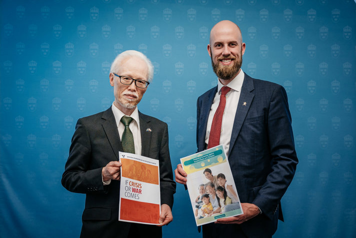 Japans ambassadör Noke Masaki står bredvid minister för civilt försvar Carl-Oskar Bohlin med Sveriges och Japans beredskapsbroschyrer.