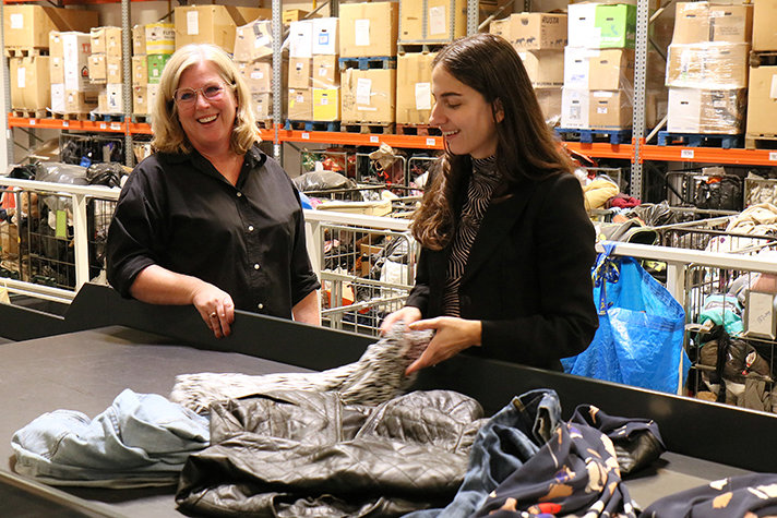 Foto på Klimat- och miljöminister Romina Pourmokhtari som sorterar kläder vid ett band.