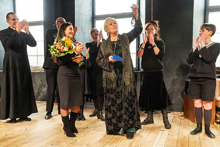 Parisa Liljestrand delar ut medalj och blommor till Christina Schollin på scen omgiven av övriga skådespelare.