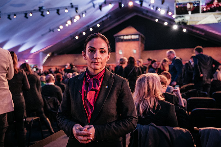 Parisa Liljestrand tittar in i kameran, i bakgrunden fler deltagare vid minnesceremonin.