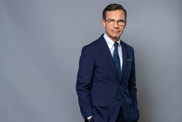 Halvfigursporträtt av statsministern mot grå bakgrund.