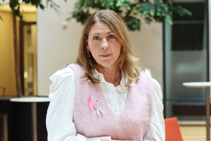 Sjukvårdsminister Elisabet Lann med två rosa bandet-symboler.