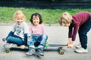 Barn som sitter på en skateboard. 