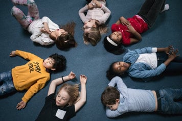 Förskolebarn ligger på en matta.