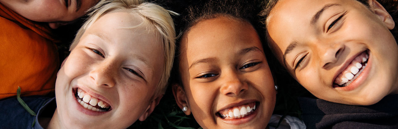 Bild på glada barn i som ligger i gräset.