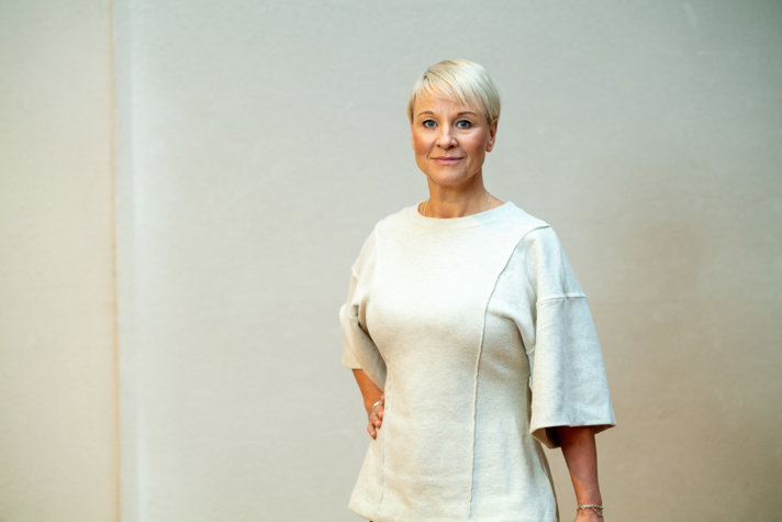 Äldre- och socialförsäkringsminister Anna Tenje i vit klänning vänd mot kameran.