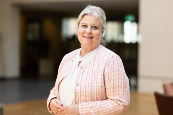 Socialtjänstministern i ljusrosa kavaj, ler mot kameran.