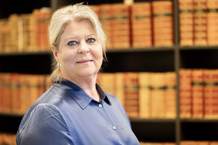 Socialtjänstminister Camilla Waltersson Grönvall står framför bokhylla vänd mot kameran iklädd blå blus.