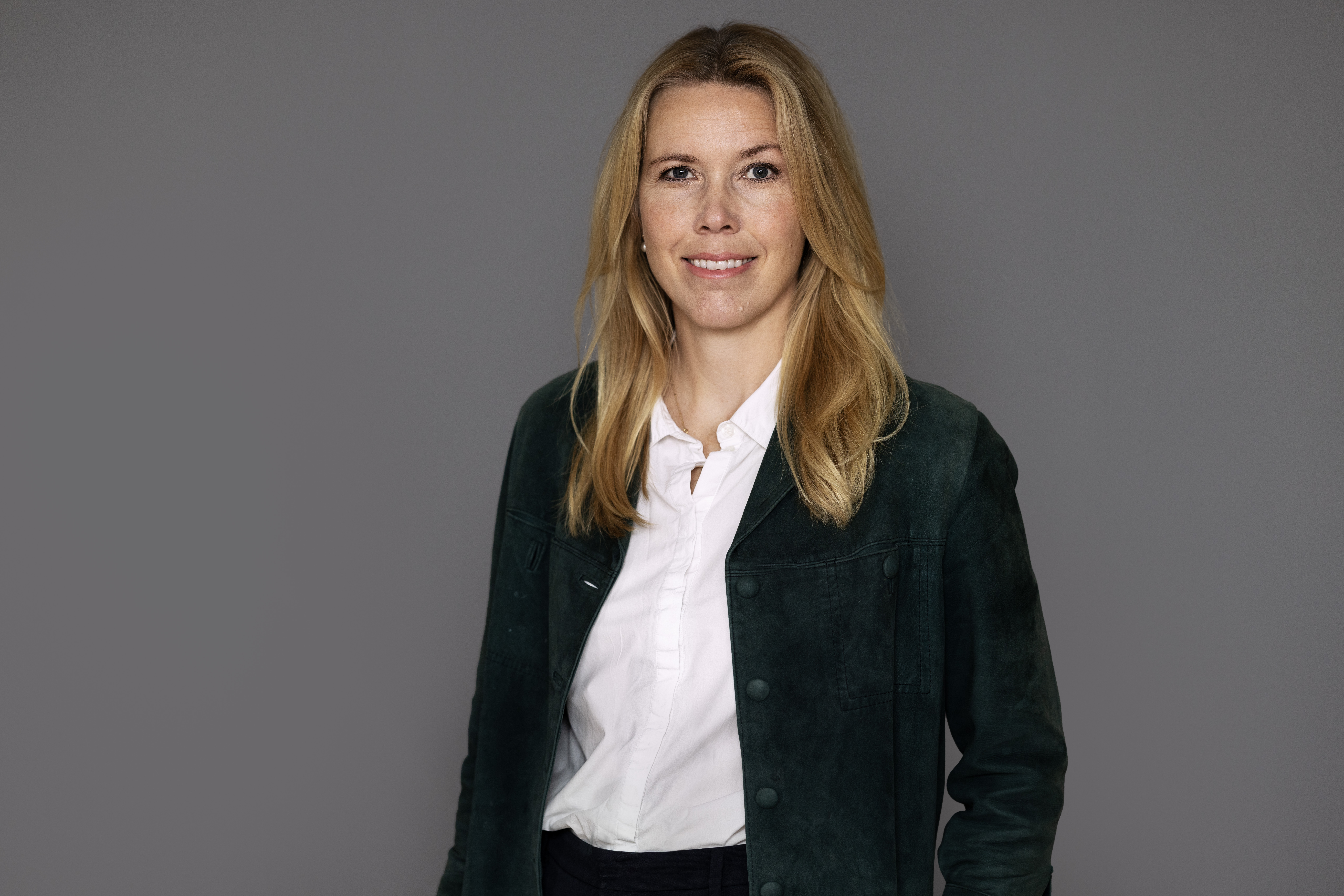 Halvkroppsporträtt på kvinna i kavaj och vit blus.