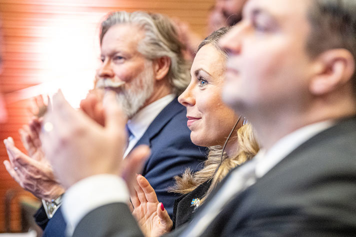 EU-ministern står tillsammans med flera personer och applåderar.