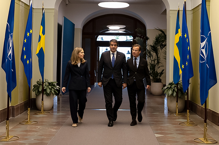 Jessica Rosencrantz, Raffaele Fitto och Ulf Kristersson går bredvid varandra i en entréhall i Rosenbad. Längs väggarna står NATO-flaggor, EU-flaggor och svenska flaggor.
