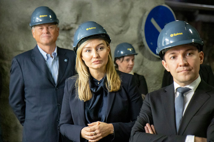 Ebba Busch står tillsammans med Finlands näringsminister i en gruva. De har skyddshjälmar på sig och i bakgrunden syns två andra personer med hjälm och en grå bergsvägg.