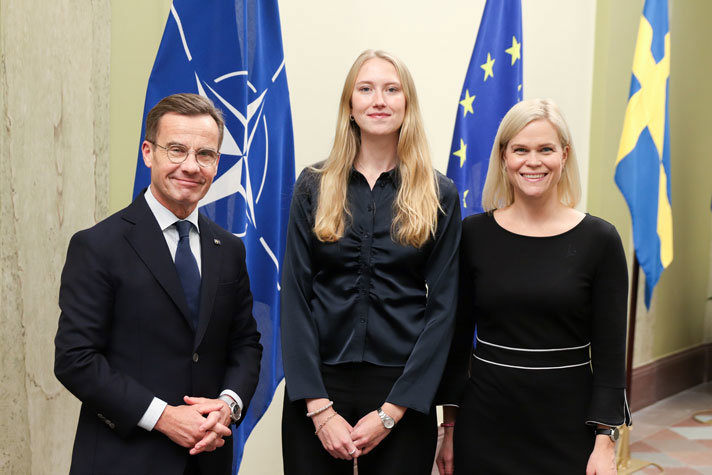 Ulf Kristersson, Clara Werner och Paulina Brandberg står framför tre flaggor