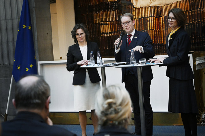 Roswall och Billström står framme vid ett podium och pratar