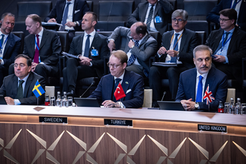Billström sitter i Natos mötesrum tillsammans med andra utrikesministrar