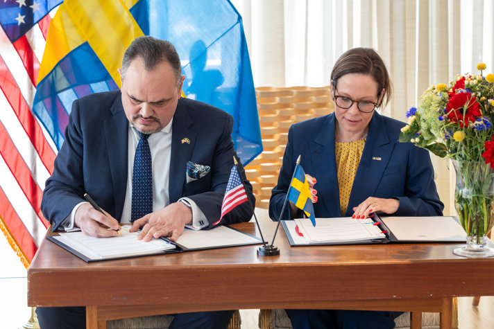 Maria Malmer Stenergard sitter vid ett bord och undertecknar ett avtal med USA.