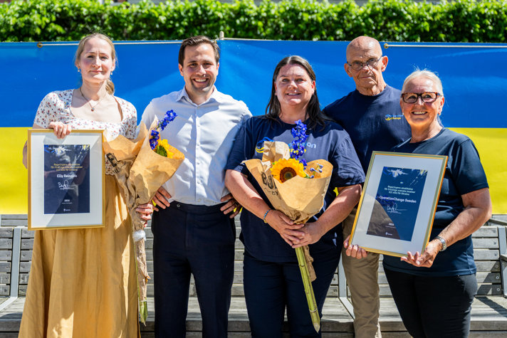 Benjamin Dousa tillsammans med Elly Reinolds och medarbetare från OperationChange. Mottagarna håller i diplom och blommor.