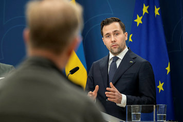 Benjamin Dousa talar på pressträff framför Ukraina-flagga och EU-flagga