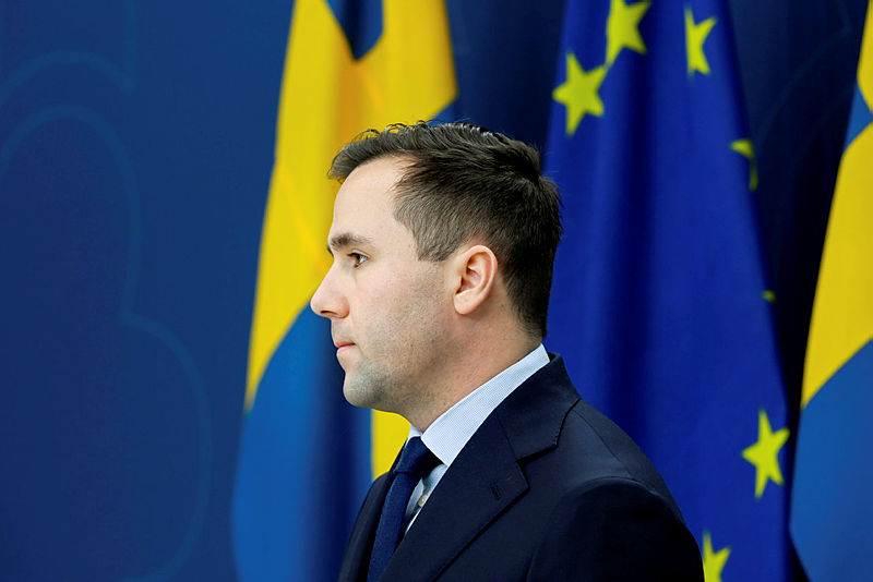 Benjamin Dousa på pressträff framför Sverigeflagga och EU-flagga.