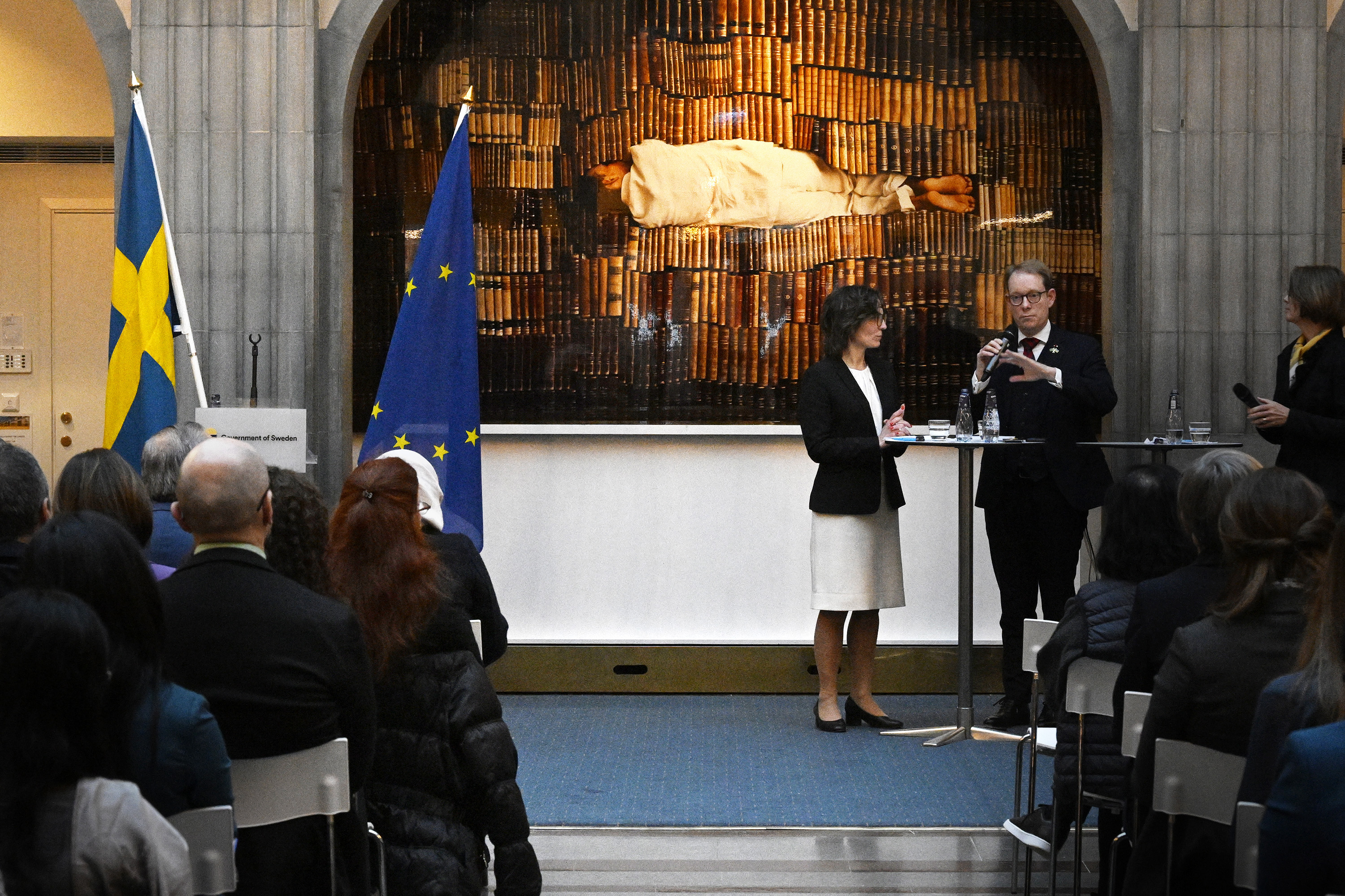 Billström och Roswall står framför publik och pratar.