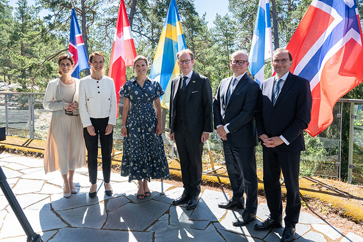 Gruppbild framför de nordiska flaggorna utomhus