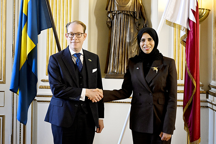 Billström och Al-Khater skakar hand framför flaggor