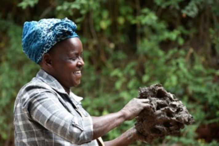 Kvinna som ler och håller i en bit lera.